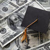 graduation cap on a pile of dollar bills 